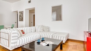 Ein modernes Wohnzimmer mit einem gestreiften Sofa, einem Glastisch und einem roten Schrank.