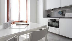 A modern kitchen with white cabinetry, a dining table, and chairs.