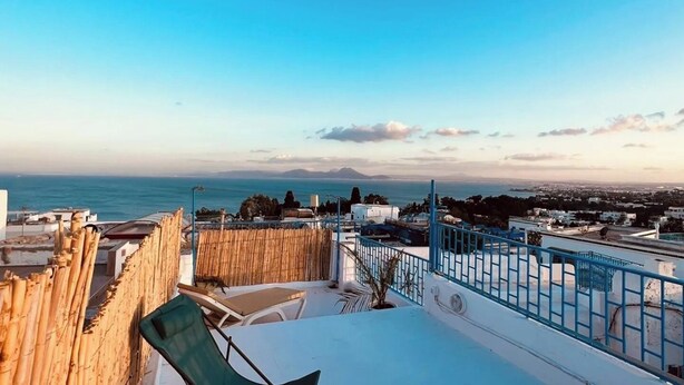 Eine Dachterrasse mit Blick auf das Meer und ferne Berge.