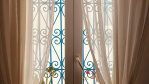 Ein Zimmer mit Blick durch ein Fenster, das mit dekorativen Metallstreben und transparenten Vorhängen versehen ist.