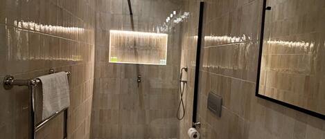 A modern bathroom with a large mirror, a sink, and a shower.