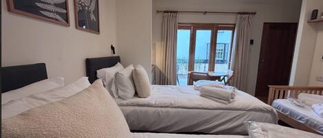 Habitación de hotel con dos camas, un balcón y vistas al exterior.