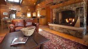 A cozy living room with a stone fireplace, leather sofa, and a wooden coffee table.