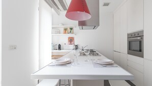 A modern kitchen with white cabinetry, a built-in oven, and a pendant light above the island. - Italianway - Palestrina 31 (Milan)