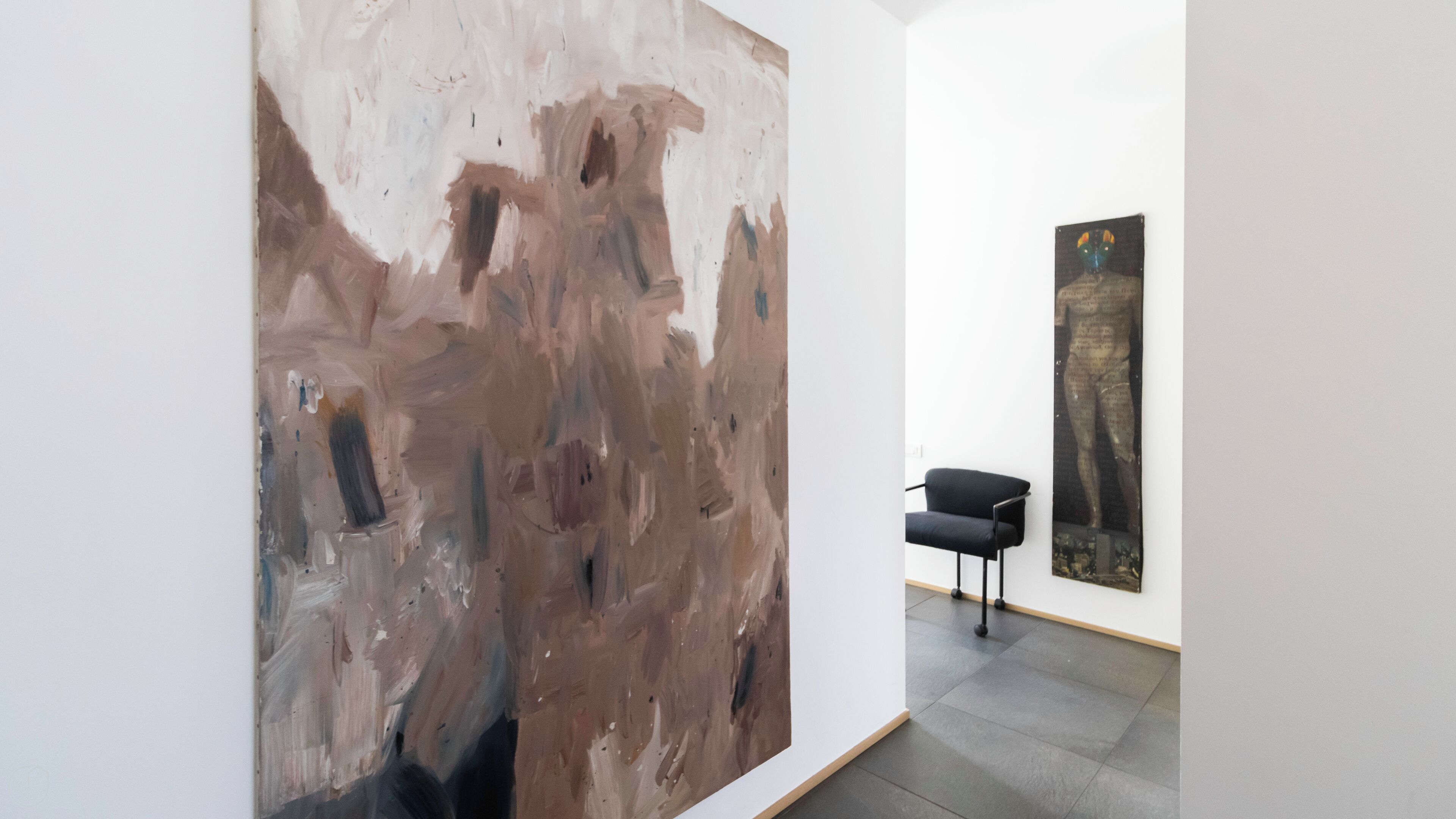 Een kunstgalerie met een groot abstract schilderij en een kleiner kunstwerk aan de muur.