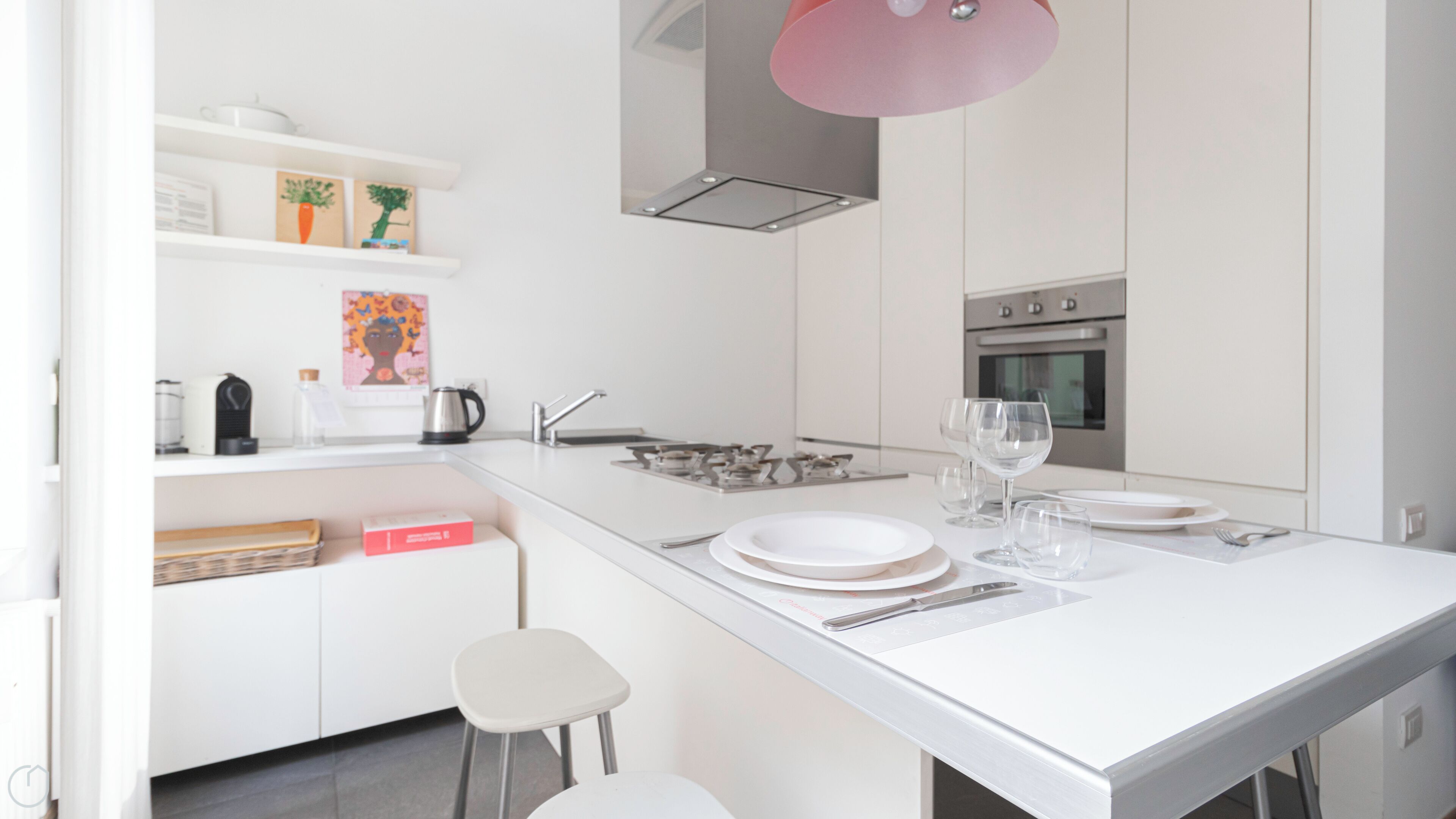 Una cocina moderna con armarios blancos, una isla central con asientos, una estufa a gas y un horno de acero inoxidable.
