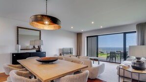 A modern living room with a dining area, large windows, and a view of the outdoors. - Mango (Funchal)