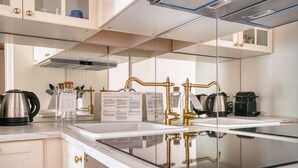 Une cuisine moderne dotée d’un plan de travail en verre, d’appareils électroménagers en acier inoxydable et d’éléments de décoration dorés.