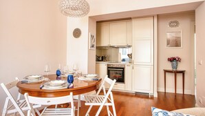 Un coin repas avec une table ronde en bois, des chaises blanches et un lustre.