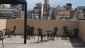A rooftop terrace with outdoor seating and a view of a cityscape including a prominent clock tower. - Studio In San Telmo- Paseo De La Cisterna- 529 (Buenos Aires)
