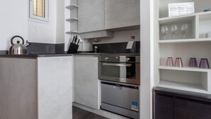 Uma cozinha moderna com forno embutido, máquina de lavar louça e chaleira sobre a bancada.