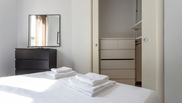 Quarto de hotel com cama, penteadeira, espelho e guarda-roupa.