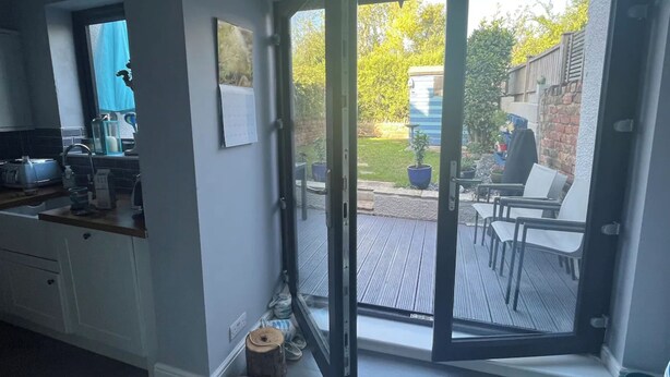 Eine Küche mit einer Schiebetür zu einem Außenbereich mit Terrasse, Stühlen und Tisch.