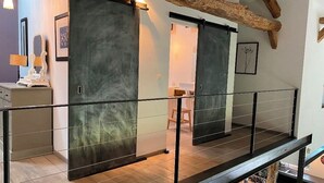 Un intérieur moderne avec une porte coulissante en verre donnant sur une pièce dotée d’un plancher en bois et d’une chaise blanche.