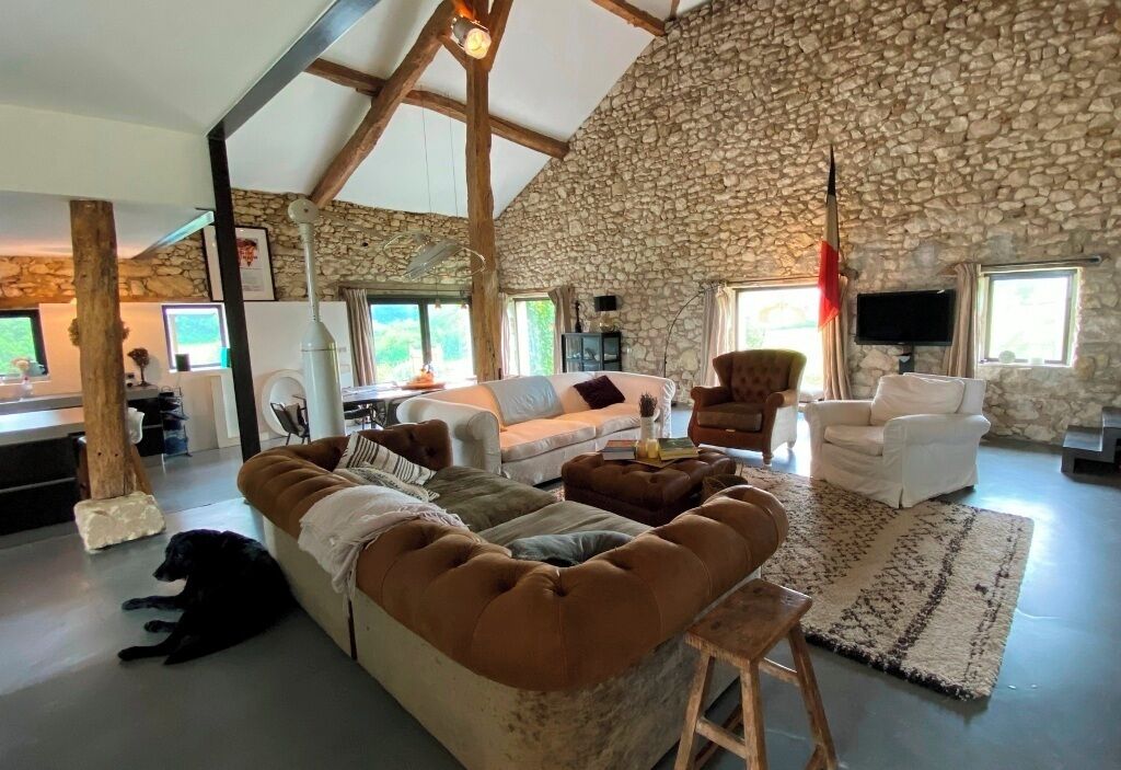 Ein großzügiger Wohnbereich mit Steinwand, hoher Decke und einer großen Couch.