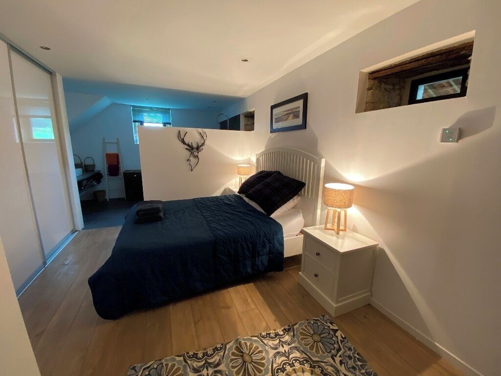A bedroom with a bed, bedside table, lamp, and a patterned rug.
