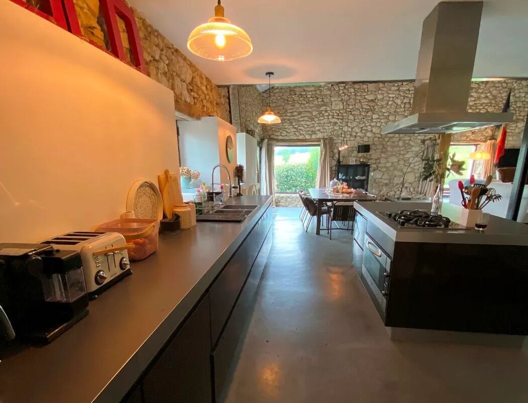 A modern kitchen with a stone wall, a central island, and a dining area with chairs.