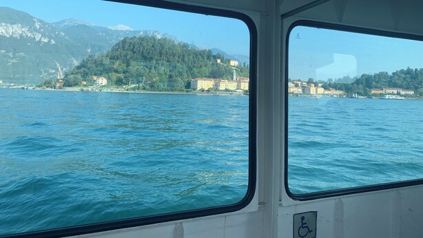 Une vue prise depuis un bateau, avec un lac limpide et des montagnes en arrière-plan.