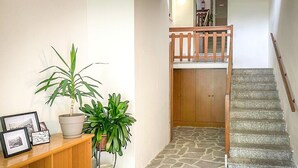 Un escalier avec une rampe en bois et un sol en pierre menant à une porte en bois.