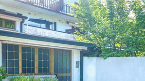 Un bâtiment à deux étages doté d’une entrée de style japonais traditionnel, d’un balcon avec une balustrade et d’un mur blanc agrémenté d’un portail.