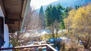 Une vue depuis un balcon donnant sur un paysage enneigé, avec des arbres et une montagne en arrière-plan.