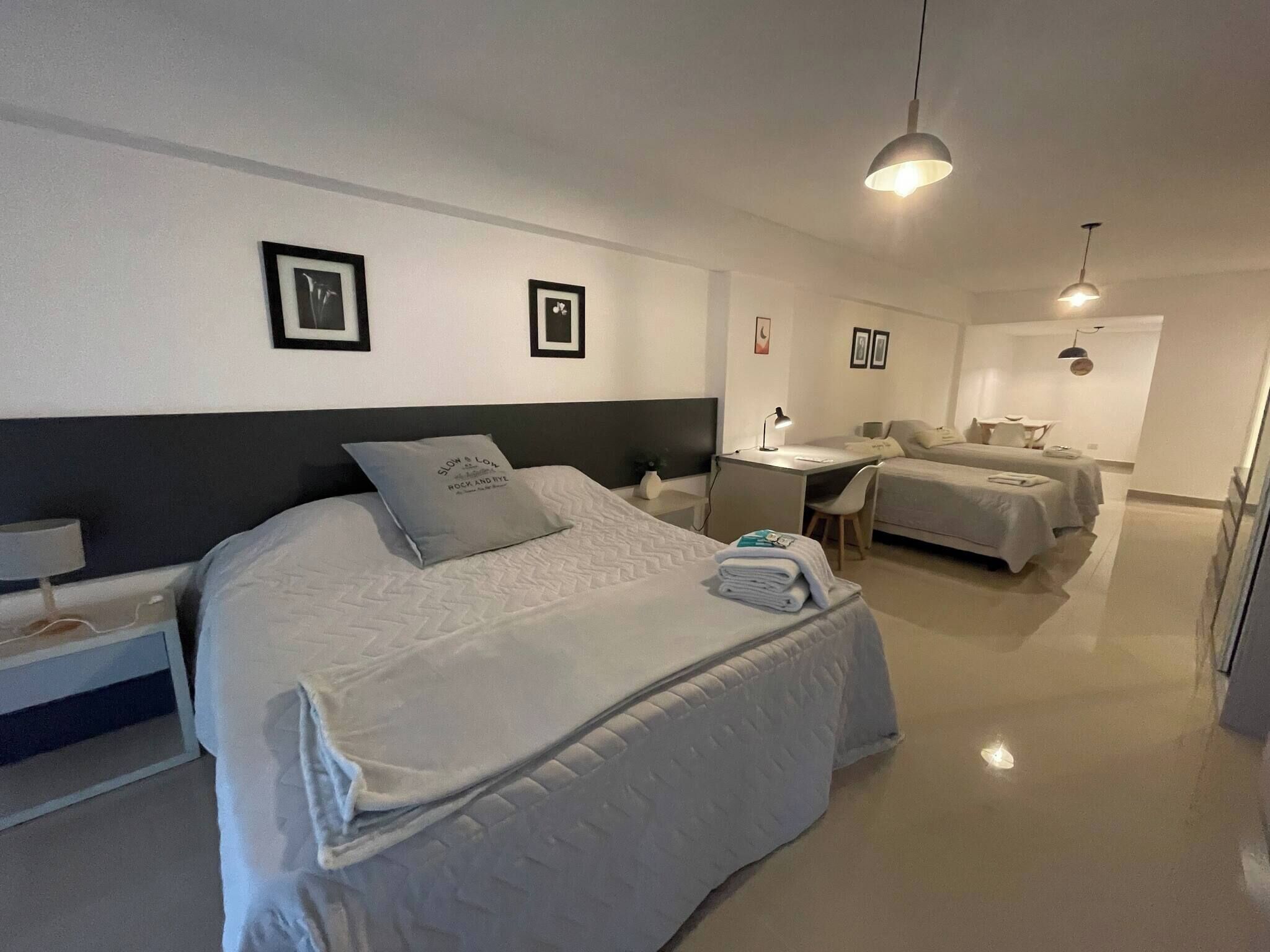 A modern hotel room with a large bed, a desk, and a small seating area.