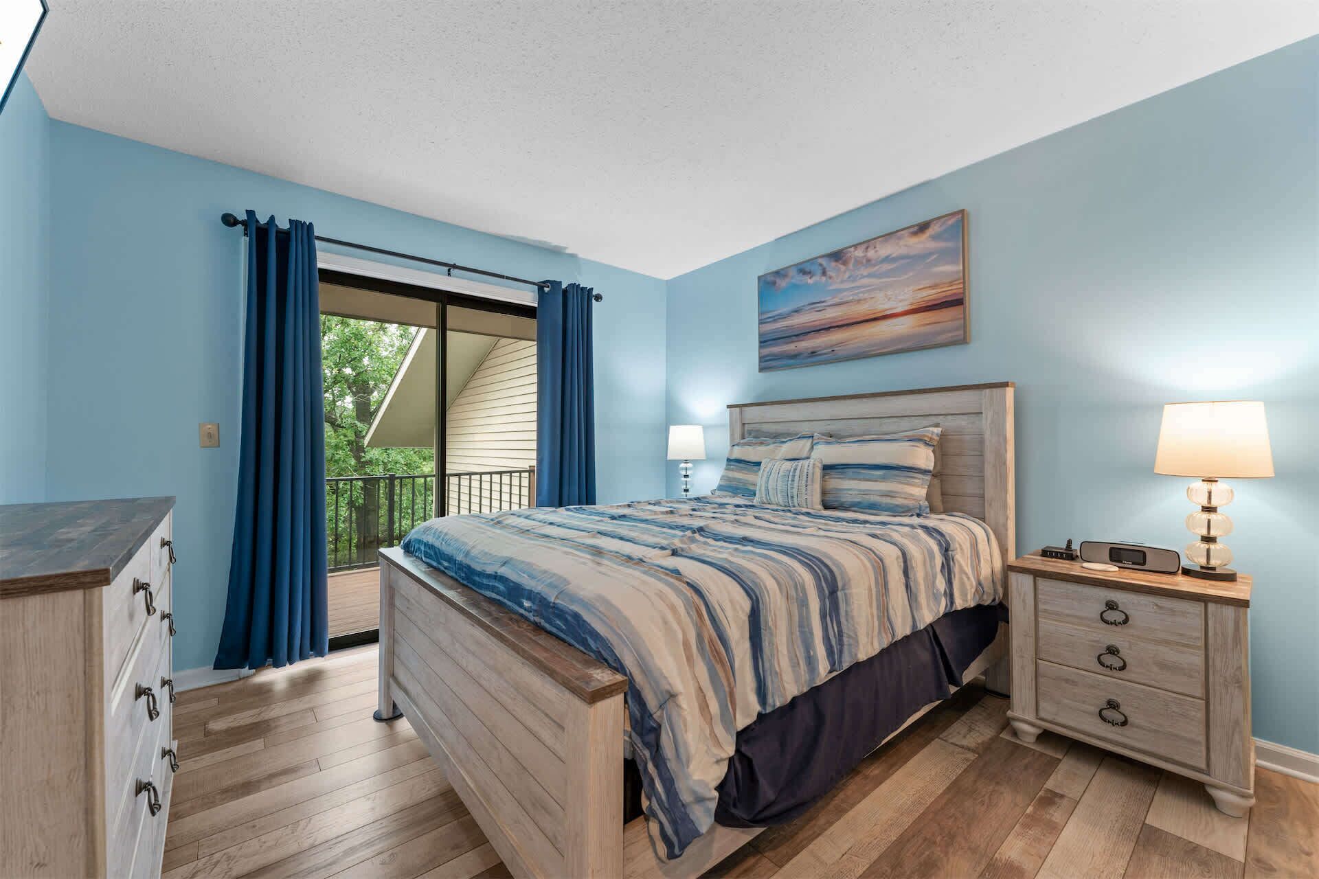 A bedroom with a bed, a nightstand, a dresser, and a painting on the wall.