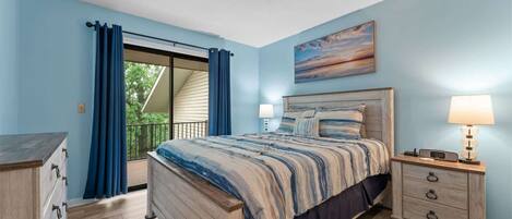 A bedroom with a bed, a nightstand, a dresser, and a painting on the wall.
