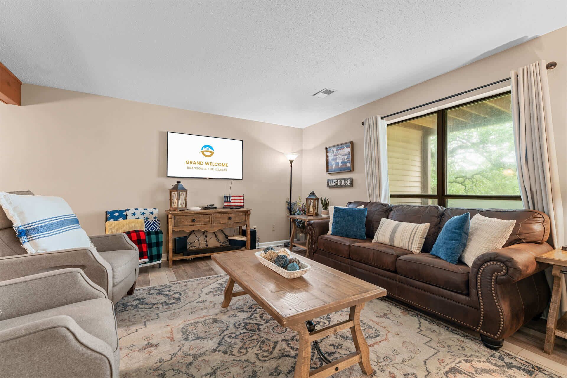A living room with a brown leather sofa, a wooden coffee table, and a television mounted on the wall.