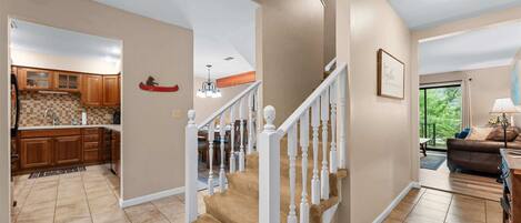 Un intérieur de maison comprenant une cuisine, un coin repas, un salon et un escalier.
