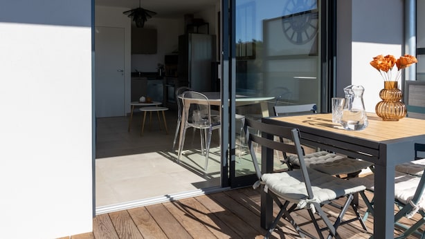 An open-plan living area with a dining table and chairs, a kitchen in the background, and a large sliding glass door leading to a patio. - La Lond'ella -  Appt à 1,5km de la mer à Porticcio (Grosseto-Prugna)