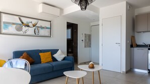 A modern living room with a blue sofa, white coffee table, and a painting on the wall. - La Lond'ella -  Appt à 1,5km de la mer à Porticcio (Grosseto-Prugna)