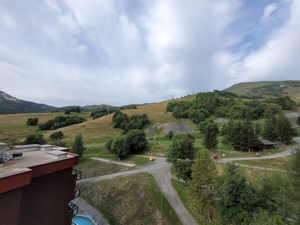 A view of a mountainous landscape with a road, trees, and a small building.