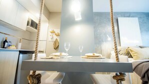 Cozinha moderna com armários brancos, micro-ondas e área de refeições com mesa posta para dois.
