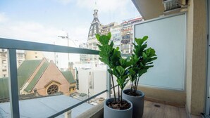 Varanda com vasos de plantas e vista para um horizonte urbano com arquitetura marcante.