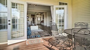An open patio with a dining table and chairs, a patterned rug, and a view into the house. - Charming Family Country Lane Cottage| 3 min to lake (Dandridge)