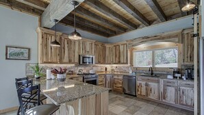 A spacious kitchen with wooden cabinets, granite countertops, and a large island. - Luxury Smoky Mountain Cabin | Amazing Views, Hot Tub, Fire Pit Near Pigeon Forge (Sevierville)