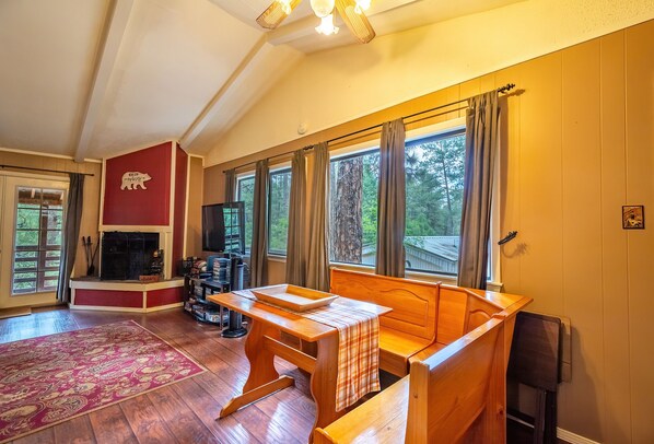 A cozy living room with a fireplace, wooden furniture, and large windows offering a view of the outdoors. - Luna Bella Hideaway Cabin, 2 bedroom, 1 bath in Ruidoso (Ruidoso)