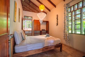 Un dormitorio con cama, ventana con cortinas, techo de madera y una lámpara colgante.