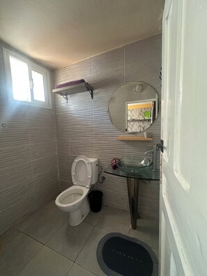 A bathroom with a toilet, a glass sink, a mirror, and a window. - Studio Loft by the Water (Haouzia)