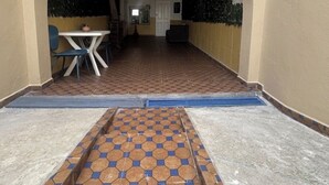 An indoor corridor with a tiled floor, a table with chairs, and a door at the end. - Studio loft waterfront (Haouzia)