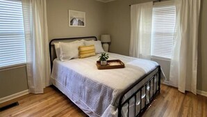 Un dormitorio con cama, ventilador de techo y ventana con cortinas.