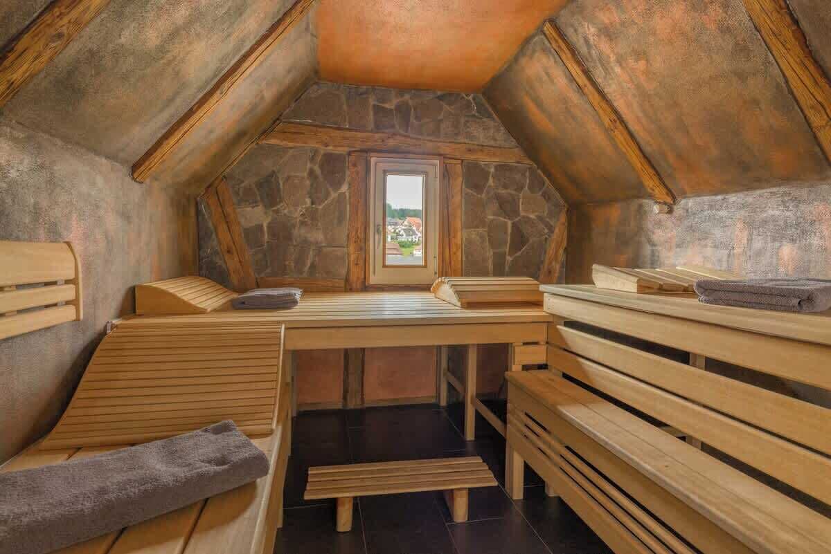 Un sauna avec des bancs en bois et un mur en pierre.