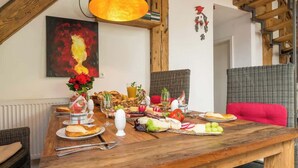 Ein Essbereich mit einem Holztisch, der für eine Mahlzeit gedeckt ist, einer Hängelampe und einem Gemälde an der Wand.