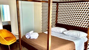 A single bed with a wooden frame and a headboard, a yellow chair, and a patterned wall. - Tiffany Home near Cefalù  (san nicola l'arena)
