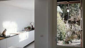A modern kitchen with white cabinets, a countertop, and a window overlooking a garden.