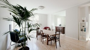 A dining area with a wooden table and chairs, a potted plant, and a modern chair.