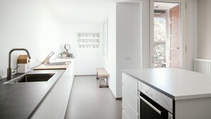 A modern kitchen with a large island, a built-in oven, and a sink.