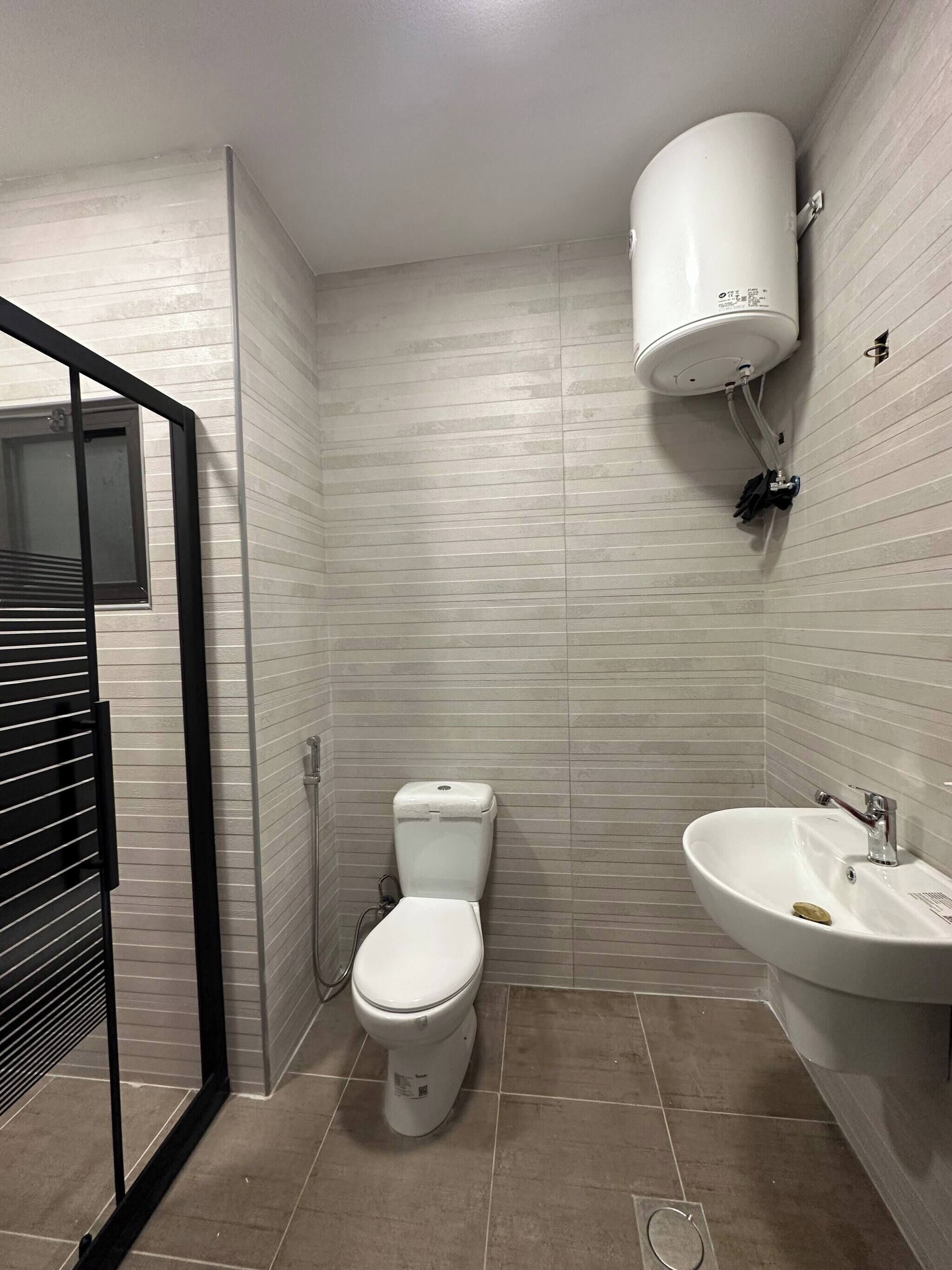 Une salle de bain équipée de toilettes, d’un lavabo et d’un radiateur fixé au mur.