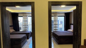 Une chambre d’hôtel avec deux lits, un grand miroir et une vue sur le paysage urbain.